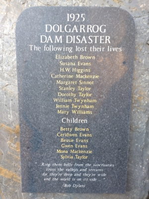 A dark stone memorial plaque mounted on a wall, engraved with a list of names.