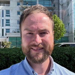 A headshot photo of Jordan Davies. He is a white man with short blond hair and facial hair.