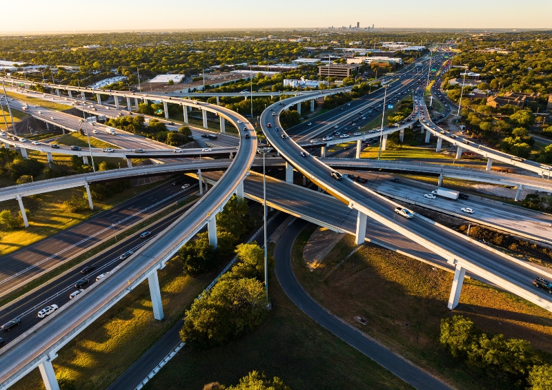 An aerial photograph of busy highway interchanges in Austin, Texas. There are three levels of highways. One on the ground level, and two elevated ones.