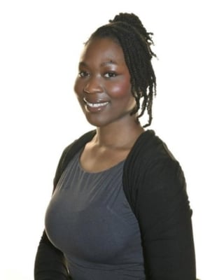 Portrait of a person with braided hair wearing a dark top and cardigan, photographed against a plain white background.