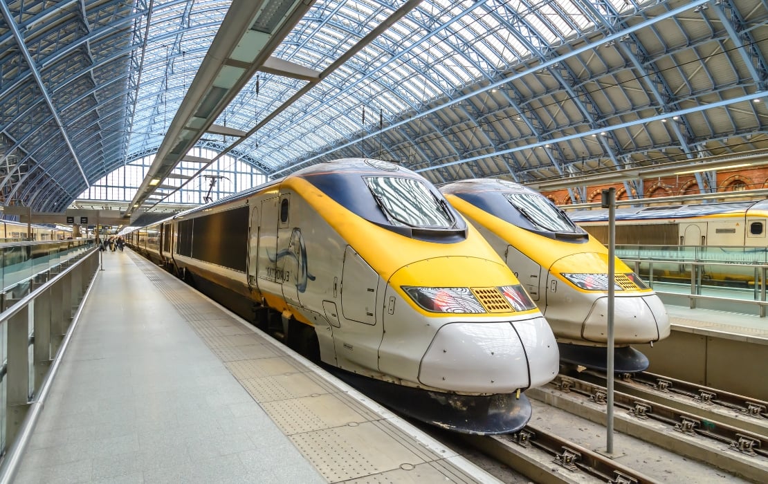 A photo of two yellow Eurostar high-speed trains at their respective platforms inside of St Pancras International Station in London, UK.
